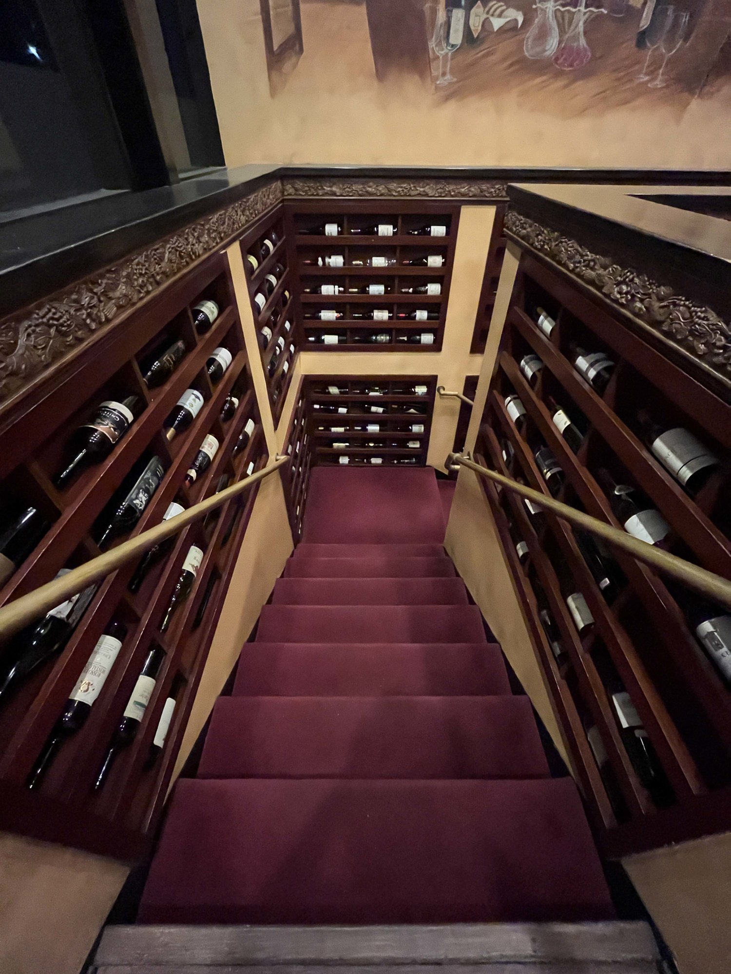 stairs down to the basement with shelves of wine bottles